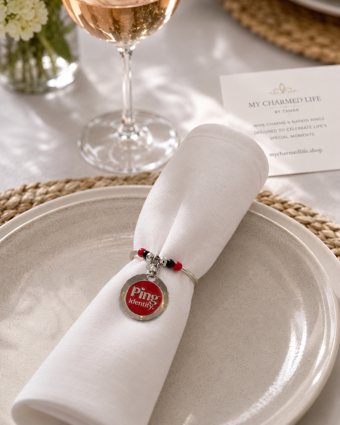 Custom company logo napkin ring with red, black and silver beads on a white napkin at a corporate event table.