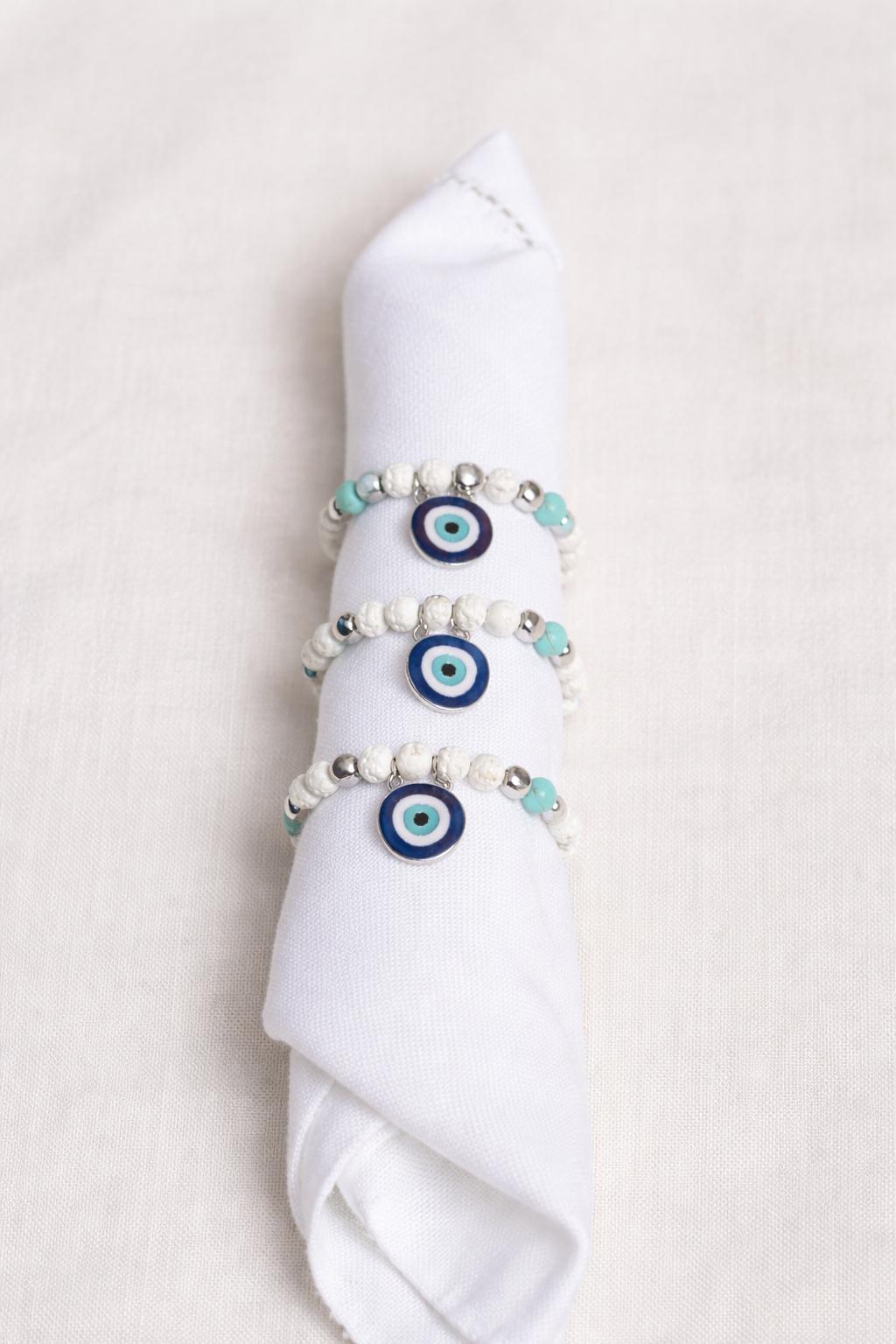 Evil eye napkin rings with blue and gold beads on linen napkins