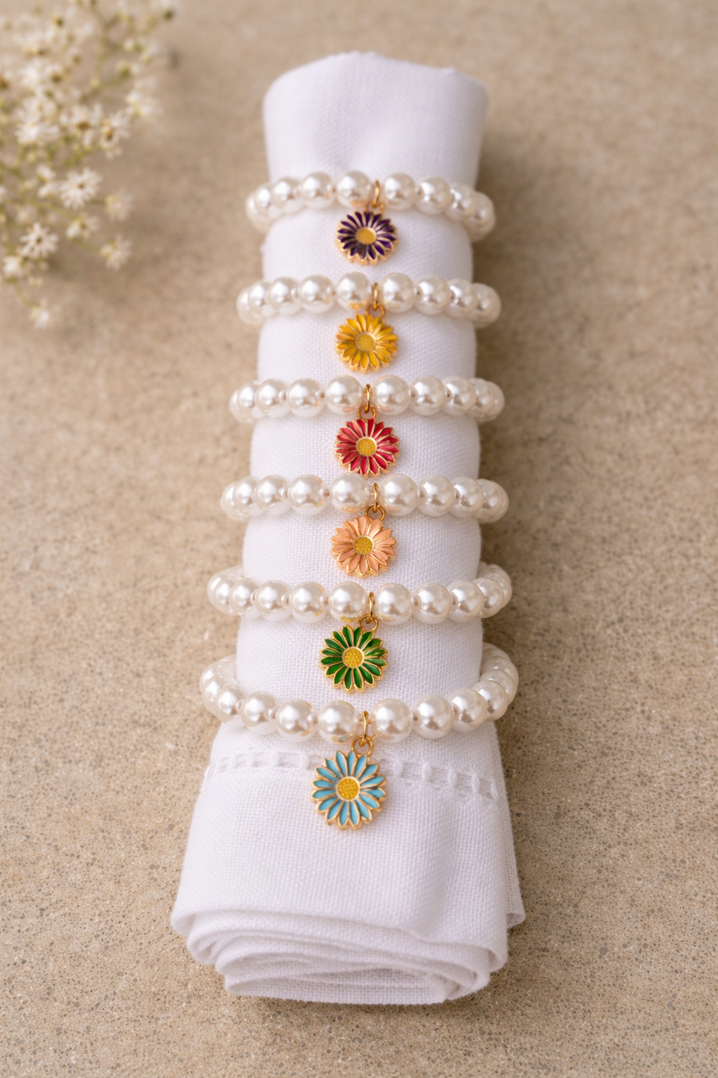 set of 6 napkin rings with colorful flowers held between pearly beads on white linen napkins for perfect table decor