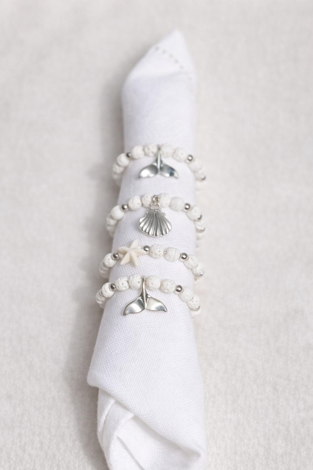 Gorgeous white and silver-tone beads with ocean inspired charms create napkin rings that will instantly elevate any table setting.