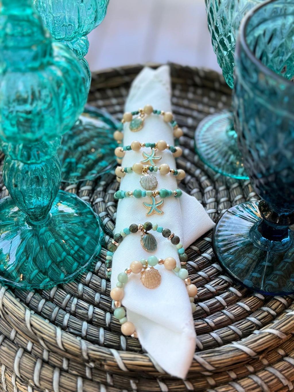 Sea collection napkin rings with taupe and turquoise beads on tablecloth
